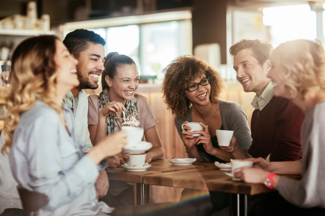 group of friends gathered and talking happily over cups of coffee